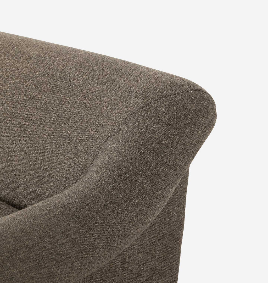 Close-up detail of a textured upholstered armchair corner in a warm taupe-brown fabric against a clean white background.