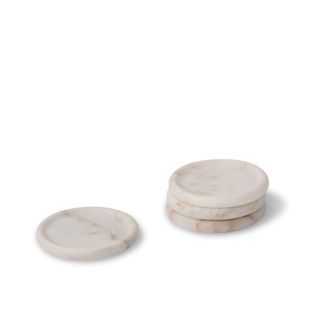 A set of white marble coasters with light grey and gold veining set against a white background. 