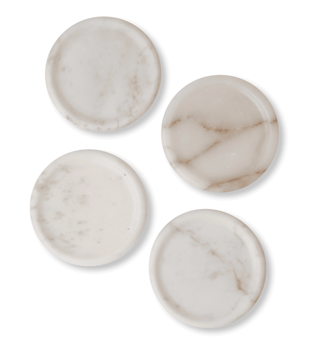 A stack of white marble coasters, set of four, with light grey and gold veining set against a white background. 