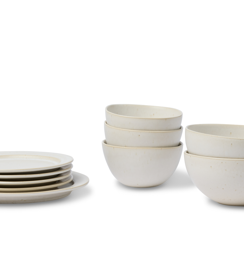 An off white dining set showing stacked pasta bowls, cereal bowls, salad plates and dinner plate shown on a white background