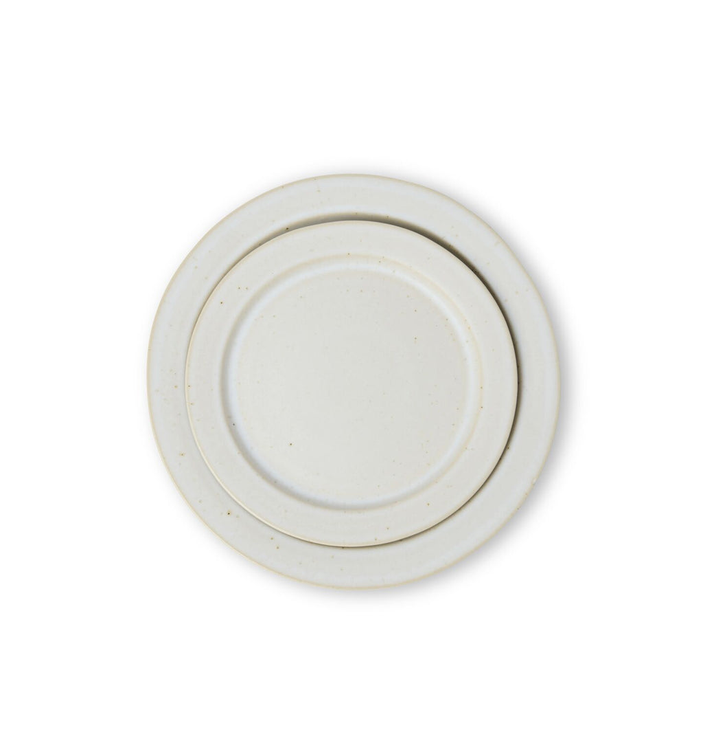 An overhead view of a ceramic salad and dinner plate finished in an off-white glaze shown on a white background