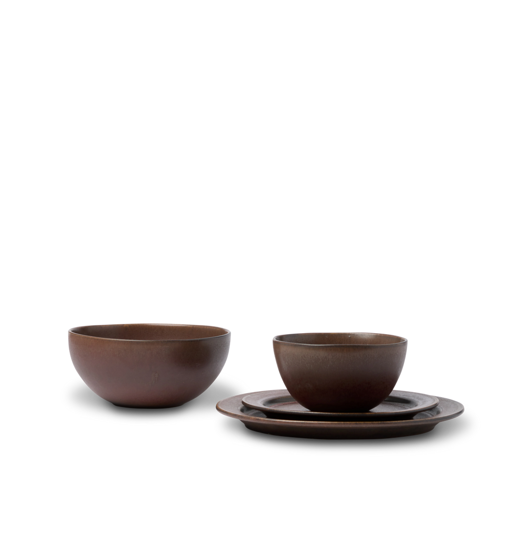 A dark reddish brown dining set showing a pasta bowl, cereal bowl, salad plate and dinner plate shown on a white background